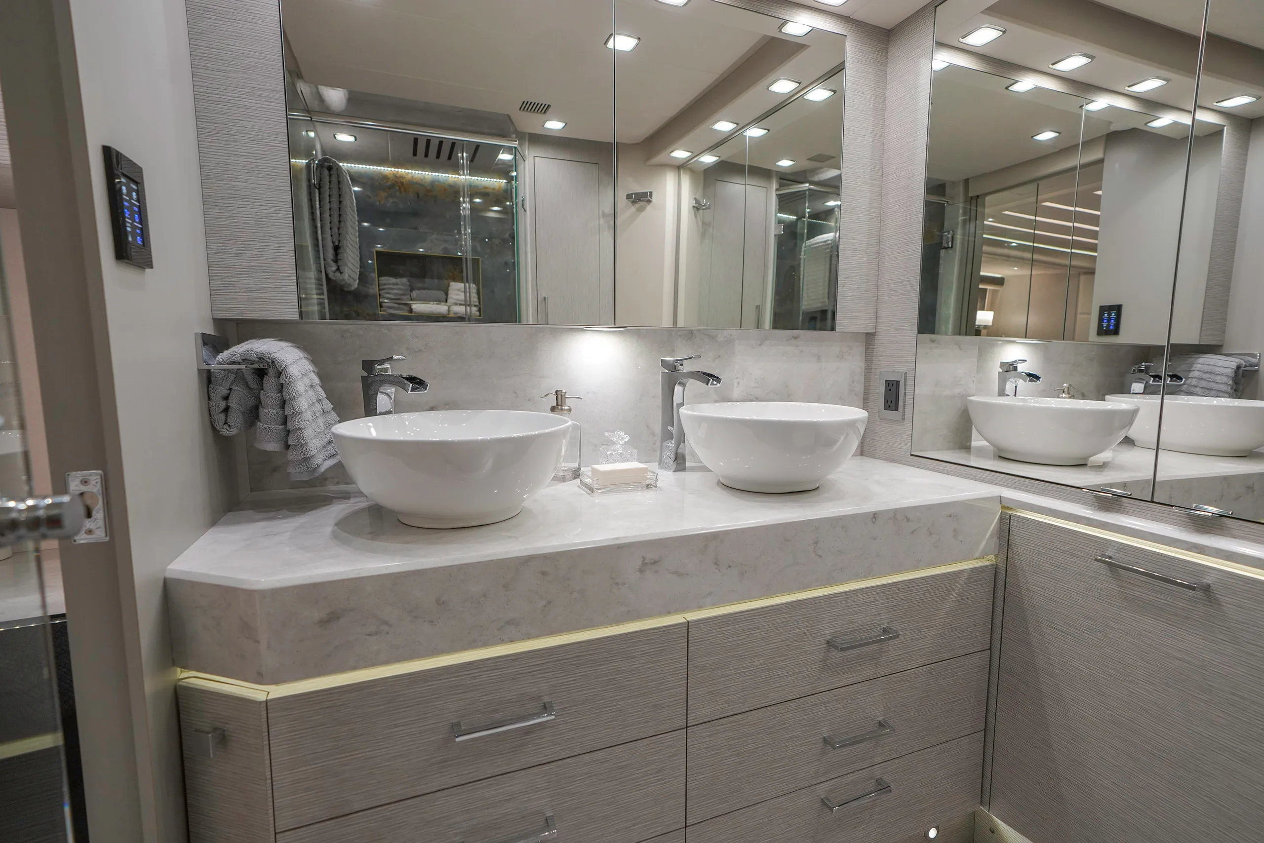 A high-end bathroom sink with under-cabinet lighting and large mirrors