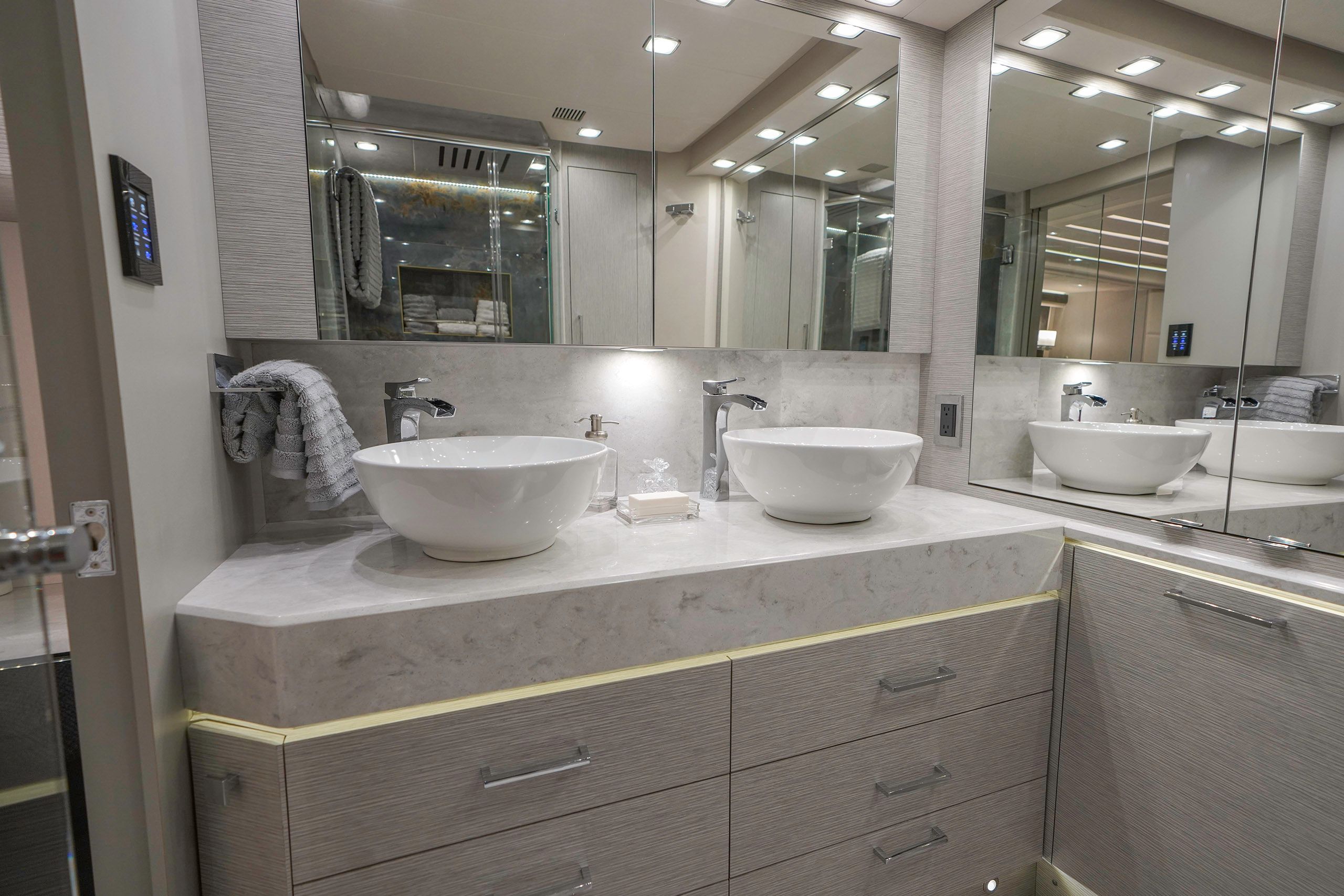 A high-end bathroom sink with under-cabinet lighting and large mirrors