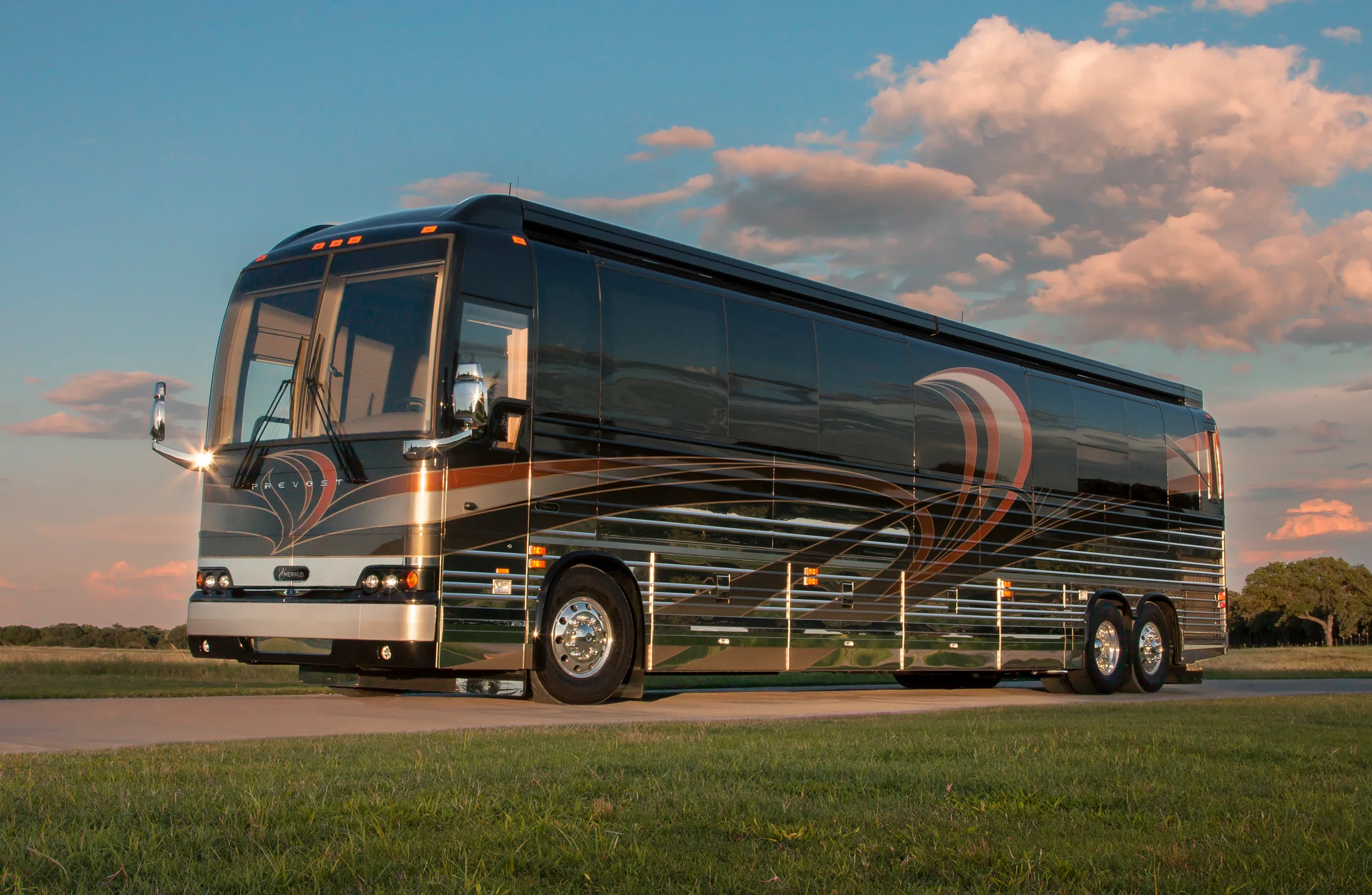 A Prevost motorcoach set against a sunset