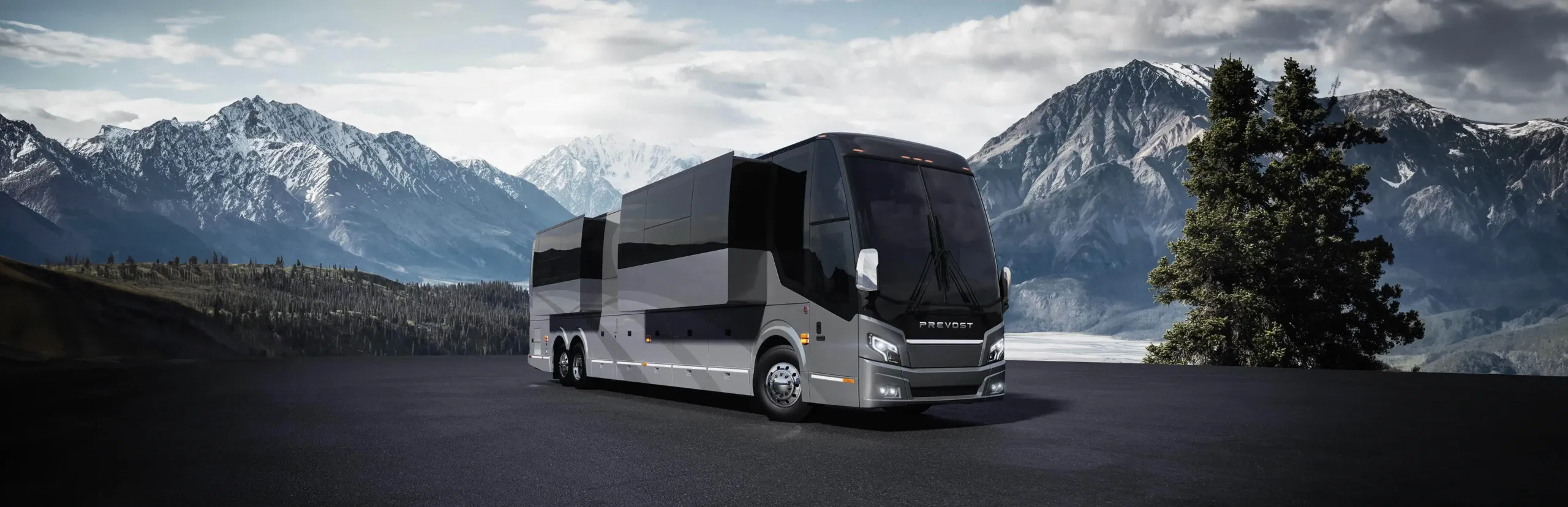 A shining silver motorcoach framed by a beautiful mountainscape